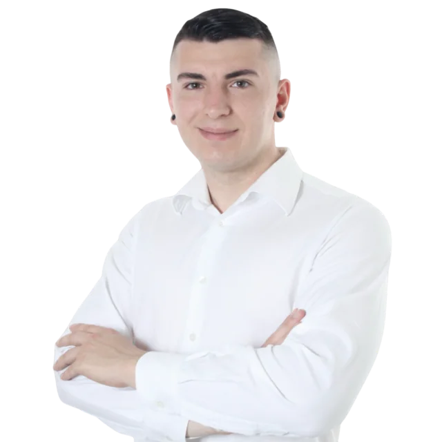 Ludovico Besana in a professional photo, wearing a white shirt and smiling with arms crossed.